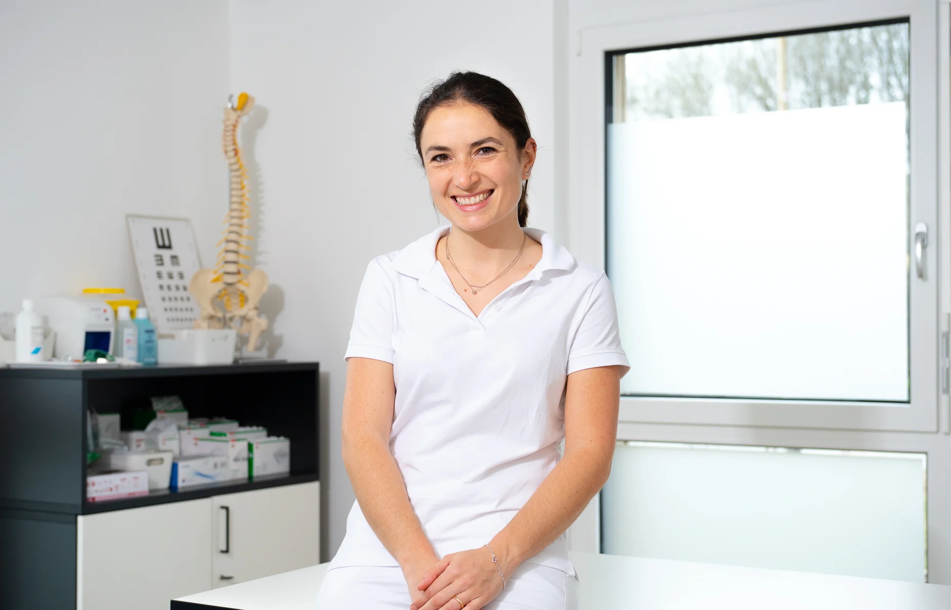 Dr. Elisa Andres Hain sitzt im selben Behandlungsraum auf der Liege
