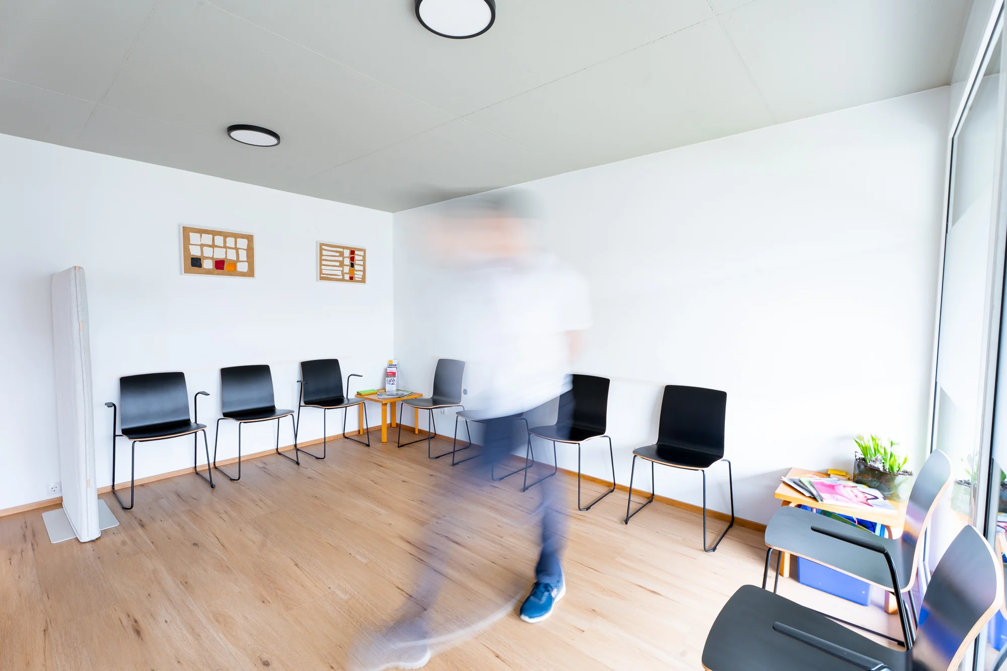 Das helle Wartezimmer mit schwarzen Stühlen